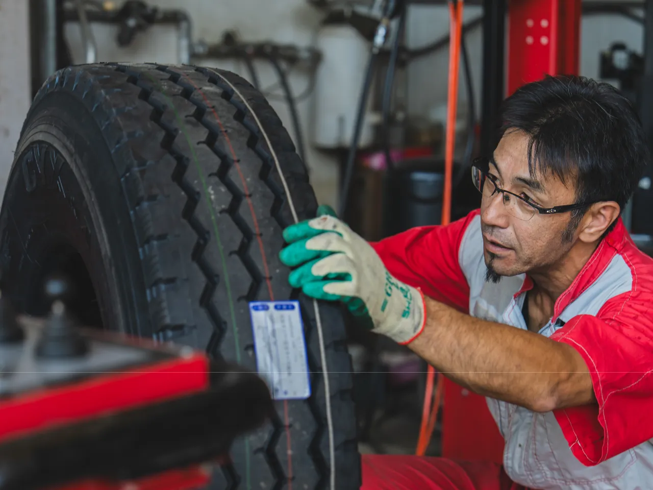 安全タイヤ（スタッフが大型車のホイールバランスをチェックしている写真）