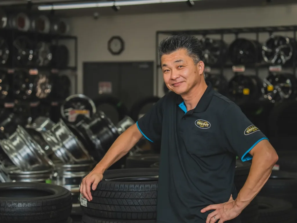 タカハシタイヤ、店長高橋（タイヤをバックに撮影）その1